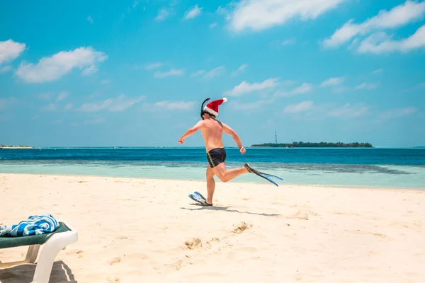 Hombre en sombrero de santa en la playa tropical — Foto de Stock