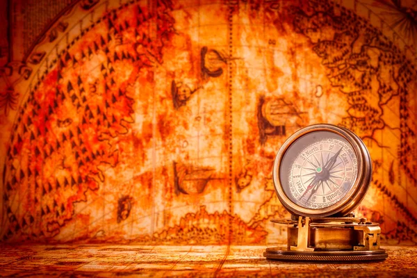 Vintage compass lies on an ancient world map.