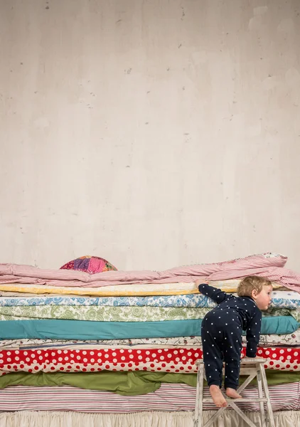 Child climbs on the bed - Princess and the Pea. — Stock Photo, Image