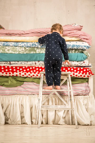 Kind beklimmingen op het bed - prinses en de erwt. — Stockfoto