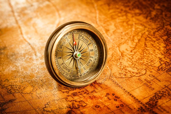 Vintage compass lies on an ancient world map. — Stock Photo, Image