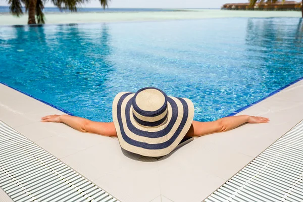 Γυναίκα σε ψάθινο καπέλο χαλαρωτικό πισίνα — Φωτογραφία Αρχείου