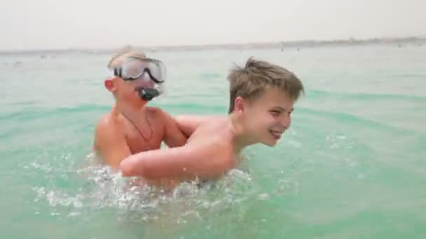 Twee jongens spelen en plezier in de zee — Stockvideo