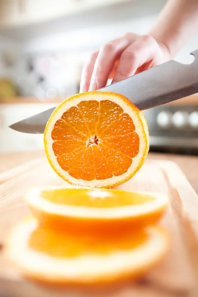 Kvinnans händer skär orange — Stockfoto