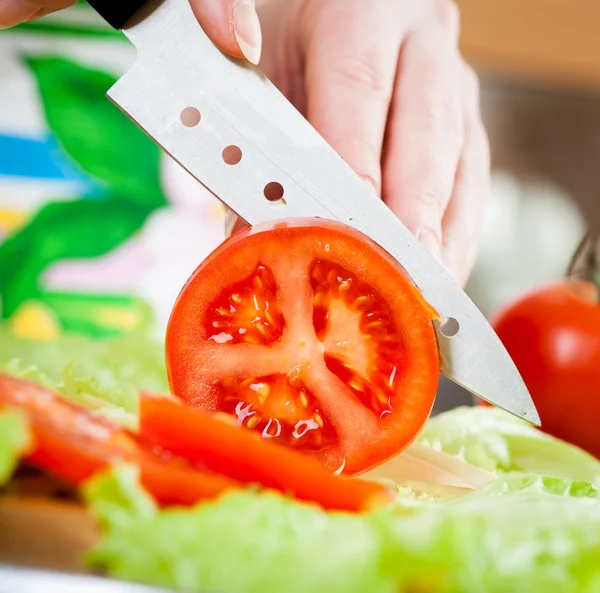 Mãos de mulher cortando tomate — Fotografia de Stock