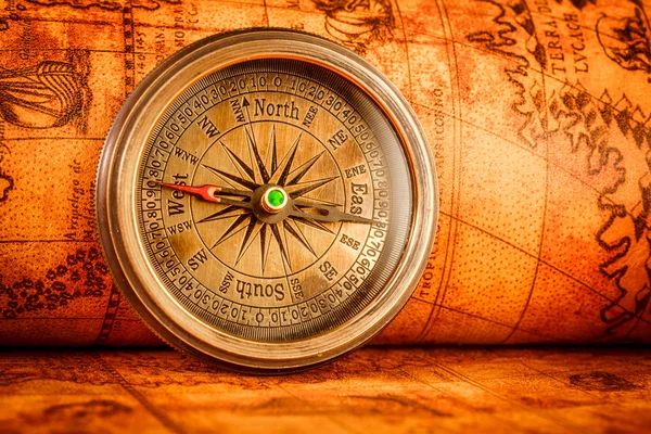 Vintage compass lies on an ancient world map. — Stock Photo, Image