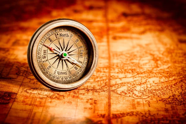 Vintage compass lies on an ancient world map. Stock Image