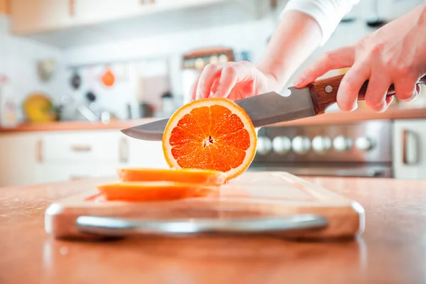 Kobiece dłonie tnące pomarańczę — Zdjęcie stockowe