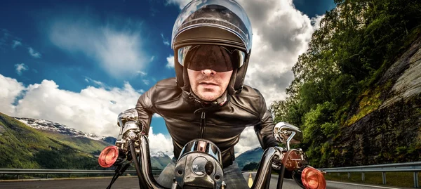 Biker em capacete e jaqueta de couro de corrida em serpentina de montanha — Fotografia de Stock