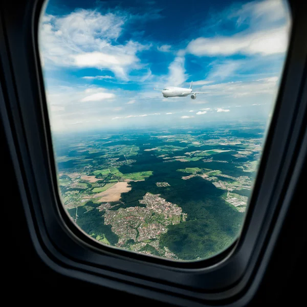 Classic image through aircraft window onto jet engine. The porthole window flies another passenger plane — Stock Photo, Image