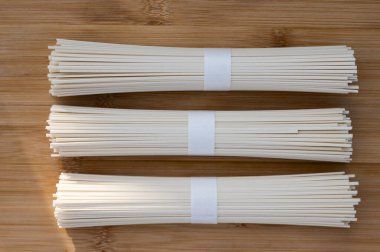 Tahta bir tahtanın üzerine dizilmiş üç paket kurutulmuş Japon eriştesinin üst görüntüsü. Doğal dokuya sahip en az gıda arkaplanı temiz..