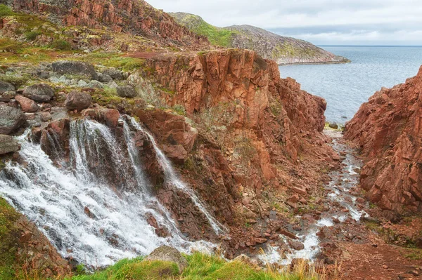 Rocks, a waterfall and the Barents Sea near the village of Teriberka