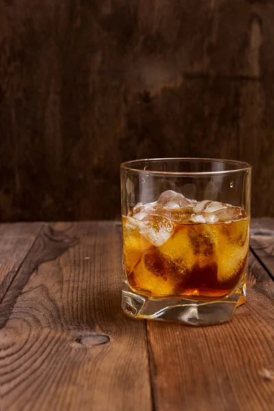 Faceted glass of whiskey with ice — Stock Photo, Image