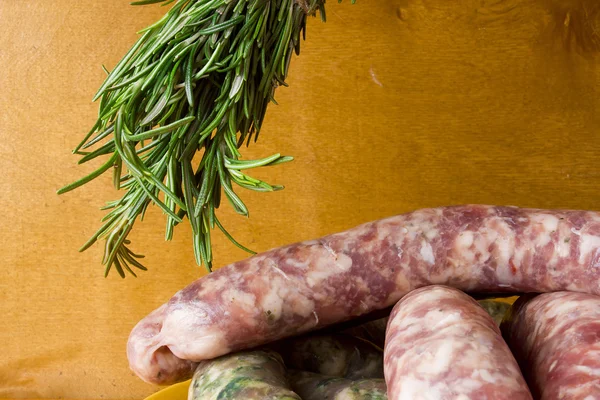 Saucisses de porc crues et un bouquet de romarin — Photo