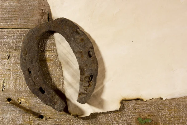 Old horseshoe and a sheet of paper — Stock Photo, Image