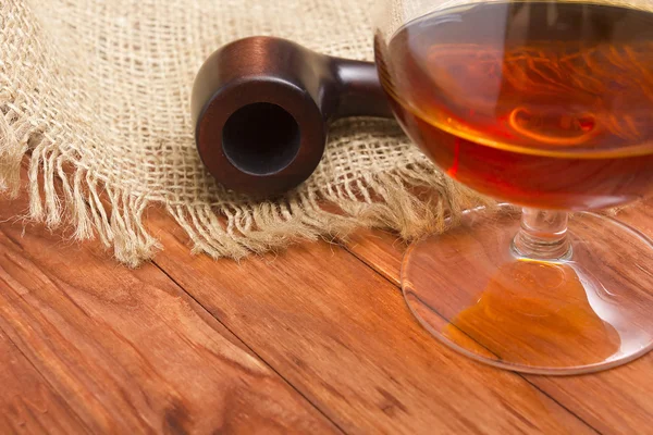 Conhaque e cachimbo de tabaco em uma mesa de madeira — Fotografia de Stock