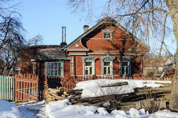 Vecchia casa in legno con mucchio di legno in inverno — Foto Stock