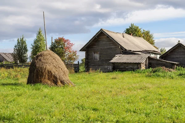 旧日志房子与干草堆在村庄里，阳光明媚的秋日 — 图库照片