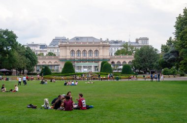Viyana, Avusturya - 02 Ağustos 2019: Viyana Şehir Parkı 'nda insanlar yeşil çimlerin üzerinde oturup dinleniyorlar.