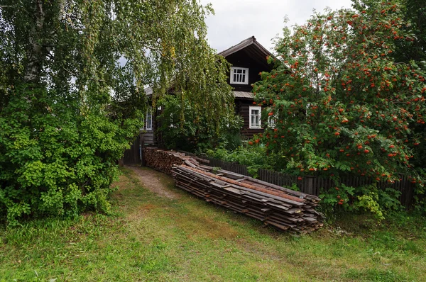Ancienne maison de campagne en bois avec pile de planches — Photo