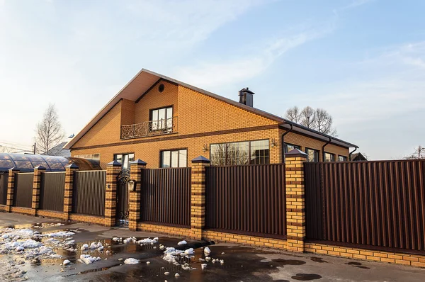 Belle maison contemporaine en brique derrière une clôture métallique — Photo