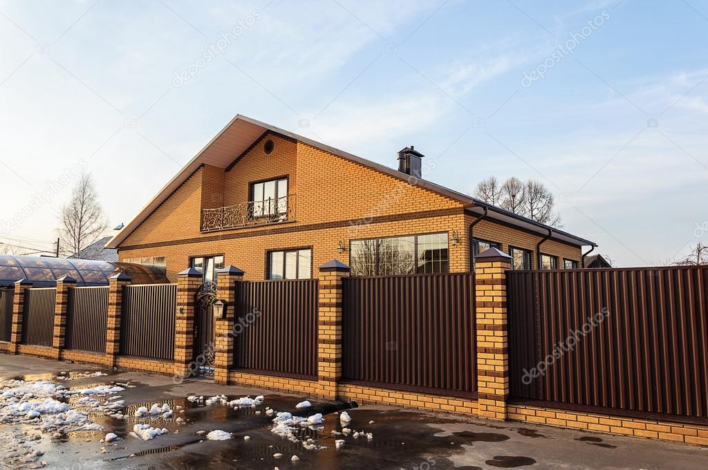 Beautiful contemporary brick house behind a metal fence