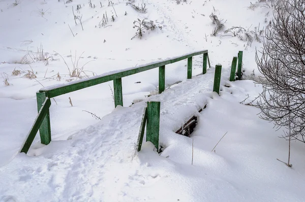 Vieille passerelle en bois couverte de neige dans le village — Photo