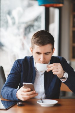 Kahve ve kahve dükkanında smartphone kullanarak yakışıklı adam