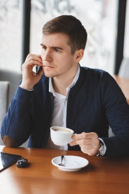 Kahve ve kahve dükkanında smartphone kullanarak yakışıklı adam