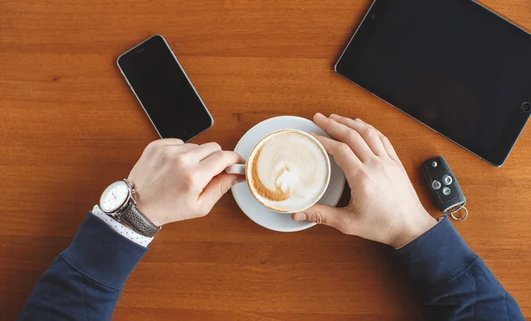 Een man's hand, een kopje koffie, Tablet PC- en auto sleutels — Stockfoto