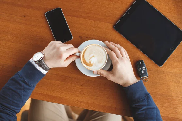 Een man's hand, een kopje koffie, Tablet PC- en auto sleutels — Stockfoto