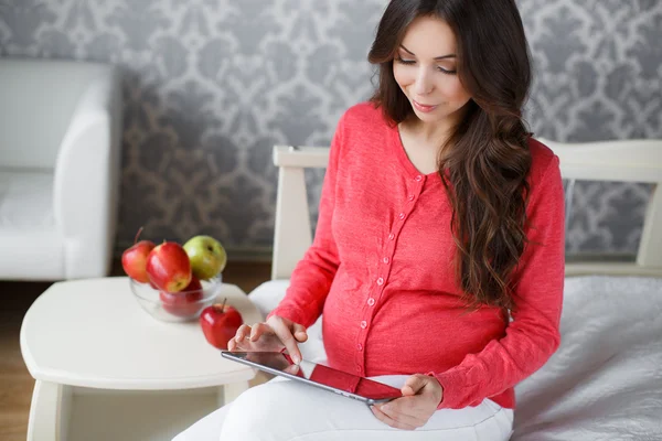 Belle femme enceinte avec un comprimé dans les mains — Photo