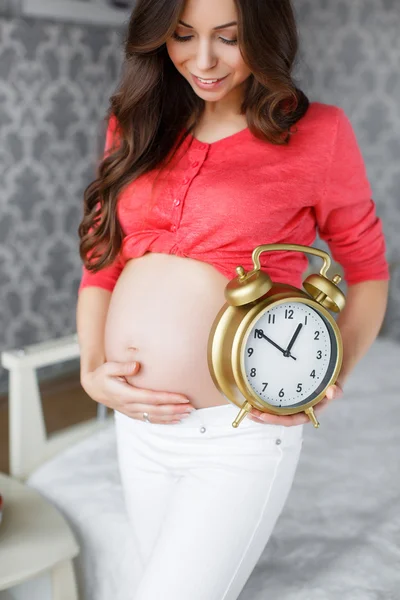 Pregnant woman with big clock in hand — Stock Photo, Image