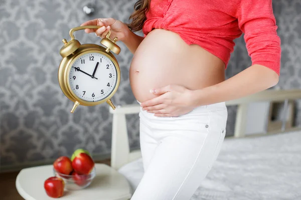 Pregnant woman with big clock in hand — Stock Photo, Image