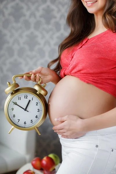 Pregnant woman with big clock in hand — Stock Photo, Image