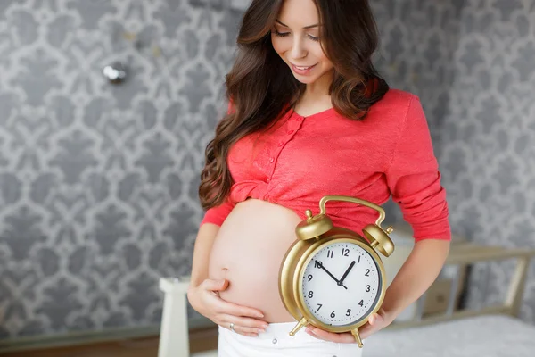 Беременная женщина с большими часами в руке — стоковое фото