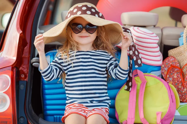 Portrait of a little girl sitting in the trunk of a car — Stock Photo, Image