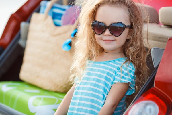 Portré egy kis lány ül a csomagtartóba az az autó — Stock Fotó