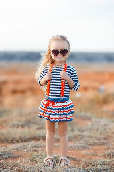 Het kleine meisje op de weide met droog gras in de zomer — Stockfoto