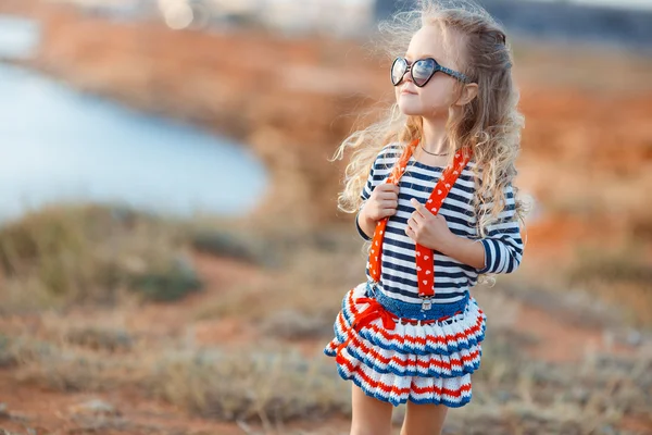 Das kleine Mädchen auf der Wiese mit trockenem Gras im Sommer — Stockfoto