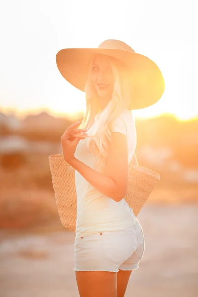 Femme en chapeau avec de grands champs, au coucher du soleil — Photo