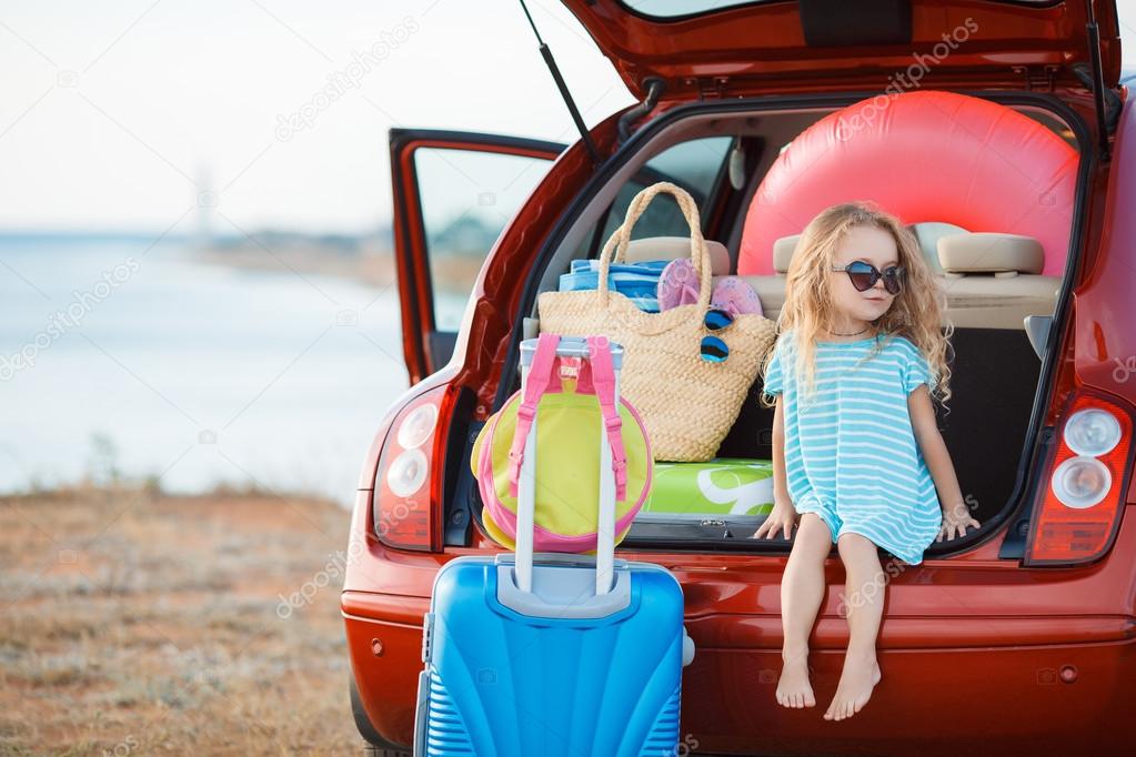 Portrait of a little girl sitting in the trunk of a car