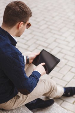 Business man with tablet computer sitting on stairs near business center.