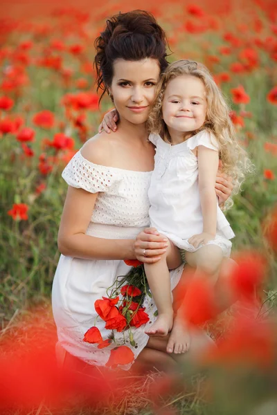 Lycklig mor och dotter i ett fält av blommande vallmo — Stockfoto