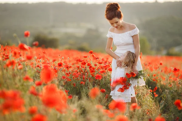Gelukkige moeder en dochter op een gebied van bloeiende klaprozen — Stockfoto