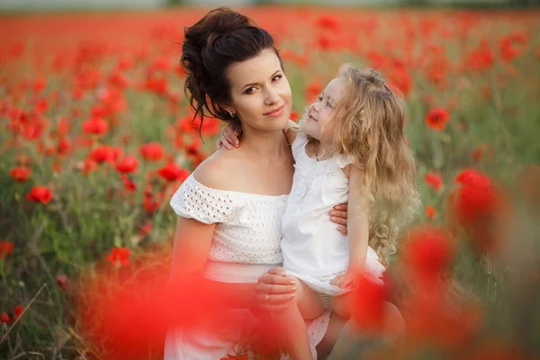 Lycklig mor och dotter i ett fält av blommande vallmo — Stockfoto