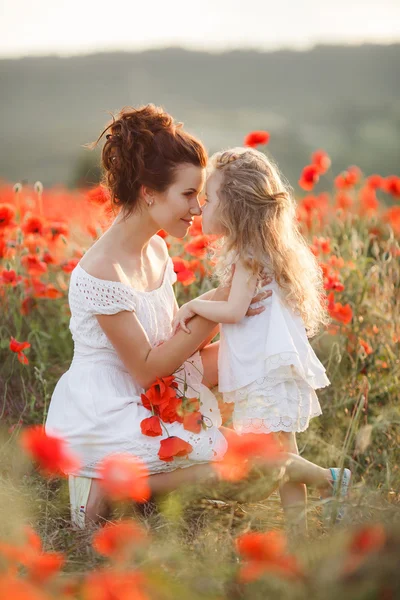 Lycklig mor och dotter i ett fält av blommande vallmo — Stockfoto