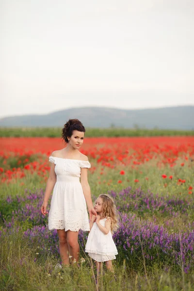 Happy mother and daughter in a field of blooming poppies — Stock Photo, Image