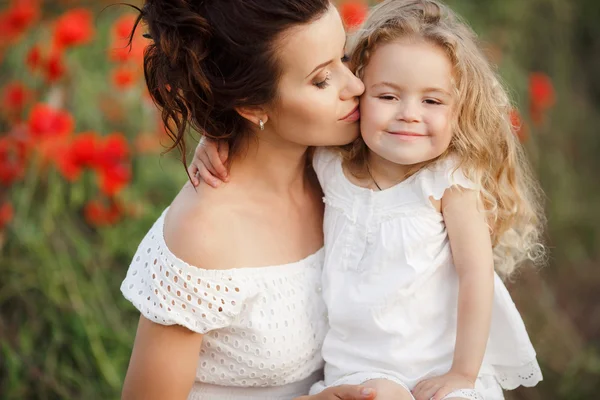 Lycklig mor och dotter i ett fält av blommande vallmo — Stockfoto