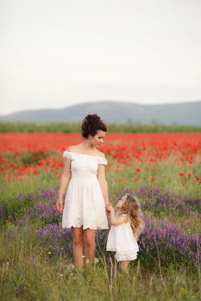 Mãe e filha felizes em um campo de papoulas florescendo — Fotografia de Stock